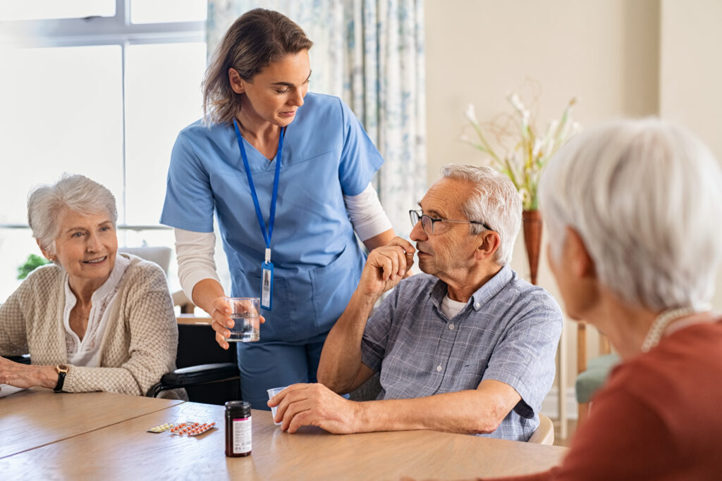 Skilled nurse giving medicine to group of seniors at nursing home.