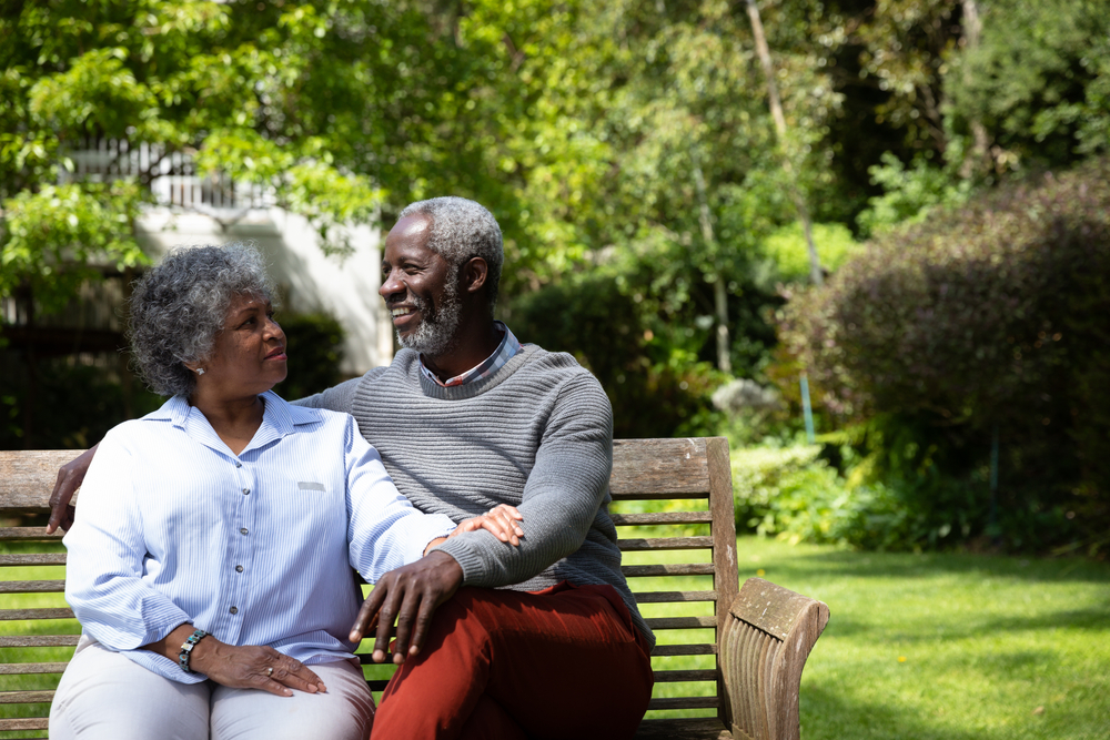 A senior African American couple sitting in the elderly care community garden.