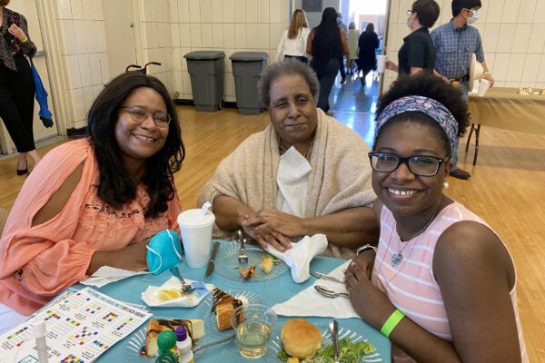 Senior woman sitting at the table with her daughter and granddaughter during Feast Day of Saint Dominic de Guzman at St. Dominic Village.