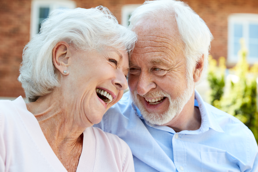 Retired couple sitting on a bench and talking in St. Dominic Village assisted living.